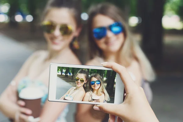 Девушки друзья фотографируются со смартфоном на открытом воздухе — стоковое фото