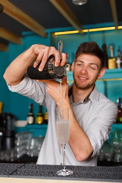 Young handsome barman pouring cocktail drink into glass — Stock Photo, Image