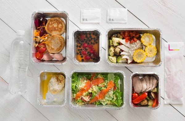 Healthy food take away in boxes, top view on wood