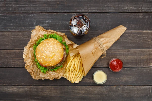 La restauration rapide à emporter. Hamburger, cola et frites sur bois — Photo