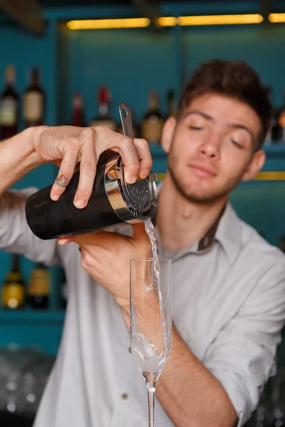 Jovem barman bonito derramando bebida de coquetel em vidro — Fotografia de Stock