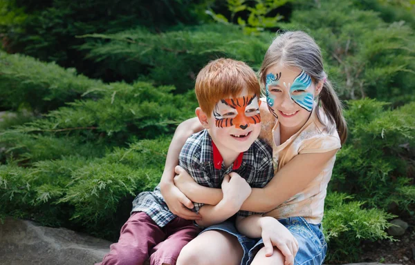 Šťastné děti, chlapec a dívka s tváří malovat v parku — Stock fotografie