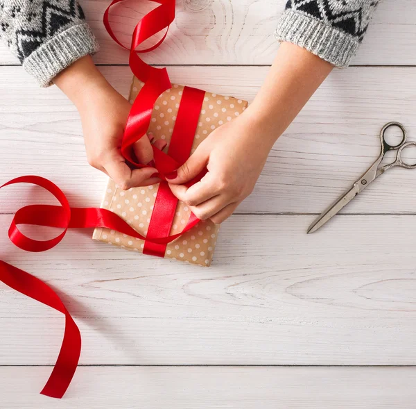 Womans hands wrapping christmas holiday present iwith red ribbon — ストック写真