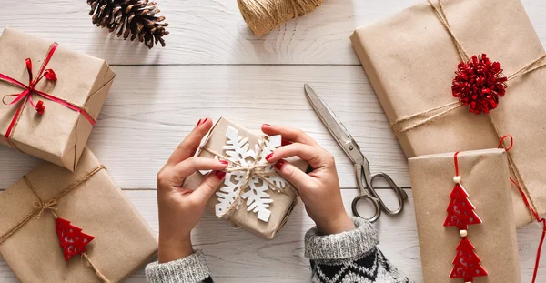 Жінки руки обгортають різдвяний святковий подарунок ремісничим шпагатом — стокове фото