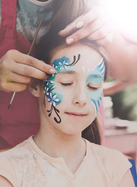 Pintura de cara de niño femenino, proceso de mariposa — Foto de Stock