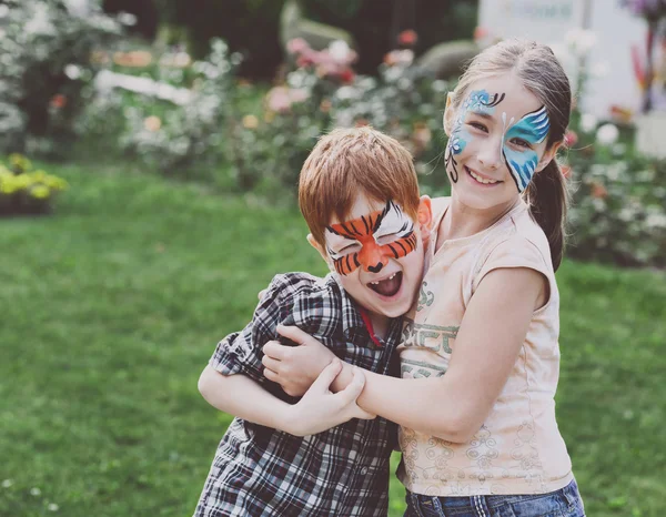 Crianças felizes, menino e menina com pintura facial no parque — Fotografia de Stock