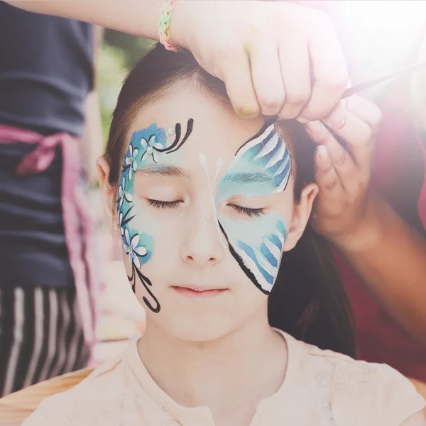 Pintura de cara de niño femenino, proceso de mariposa — Foto de Stock