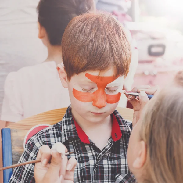 Child boy face painting, making tiger eyes process