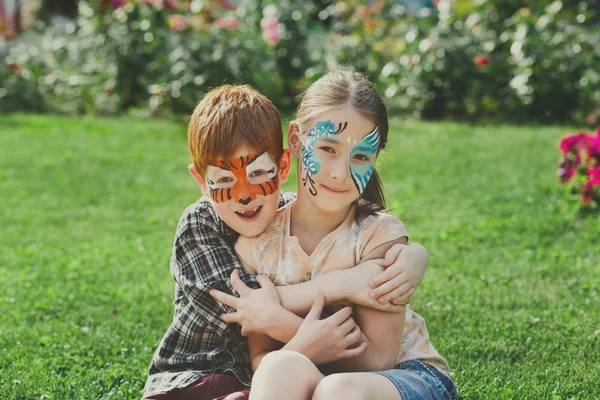 Crianças felizes, menino e menina com pintura facial no parque — Fotografia de Stock