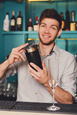Genç yakışıklı barmen içinde Bar sallayarak ve alkol kokteyl karışımı