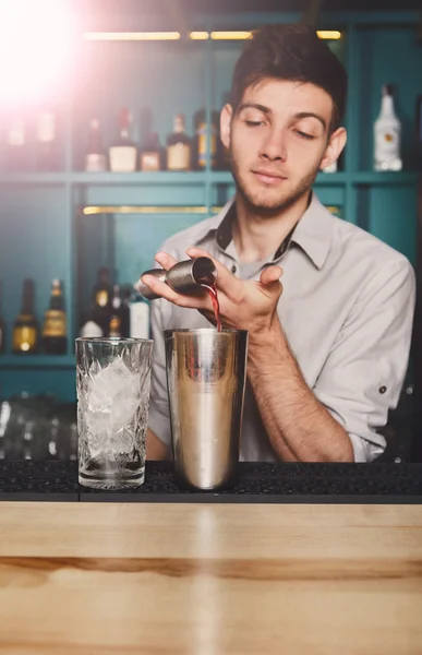 Joven barman guapo vertiendo bebida de cóctel en el vaso — Foto de Stock