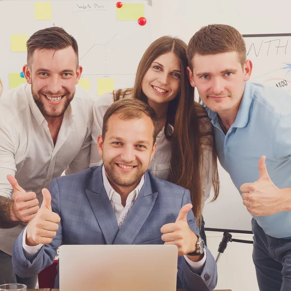 Gente de negocios feliz se unen cerca de la computadora portátil en la oficina — Foto de Stock