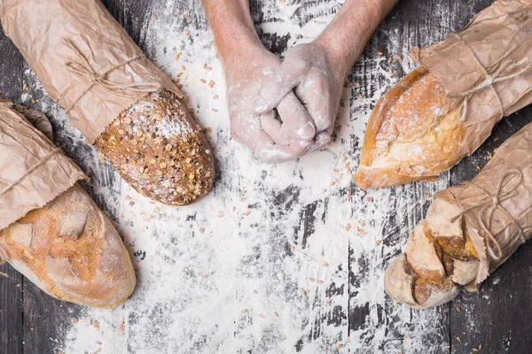 Fondo concepto panadería. Manos y tipos de pan — Foto de Stock