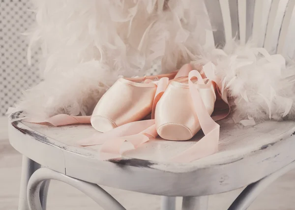 粉色的芭蕾舞足尖鞋和白色木背景上的羽毛 — 图库照片