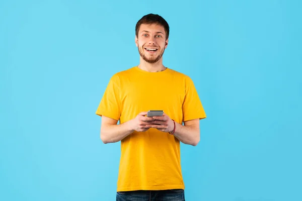 Homem surpreso usando telefone celular no estúdio — Fotografia de Stock