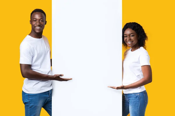 Alegre casal africano em pé por placa vazia para propaganda — Fotografia de Stock
