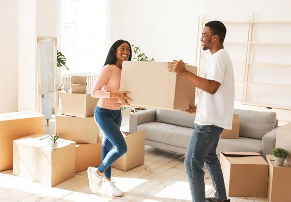 Longitud completa de hombre negro joven con su novia llevando caja de cartón en su nuevo hogar en el día de la mudanza — Foto de Stock