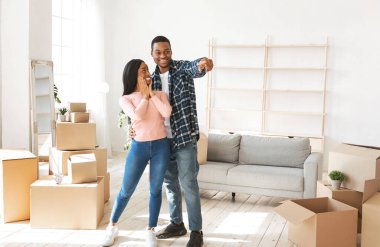 Siyah milenyum adamı heyecanlı kız arkadaşına yeni evlerinde bir şey gösteriyor.