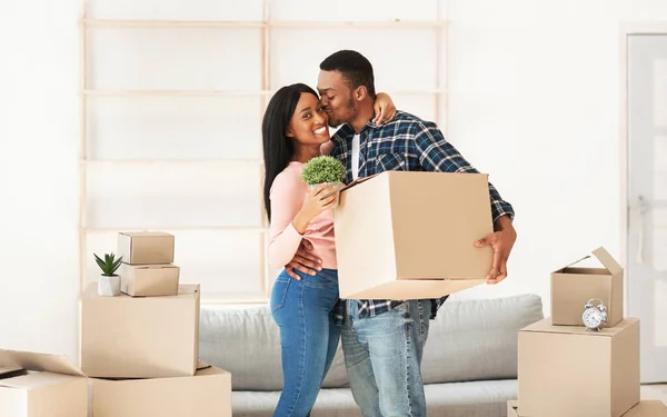 Liefdevolle zwarte man zoent zijn geliefde vrouw op verhuizing dag in hun nieuwe woning, vrije ruimte. Panorama — Stockfoto