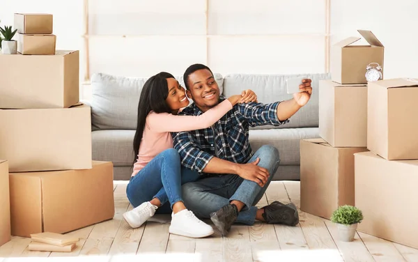 Pozitif siyah adam ve karısı kendi evlerine taşınıyorlar, kişisel eşyalarının olduğu kutuların arasında selfie çekiyorlar.