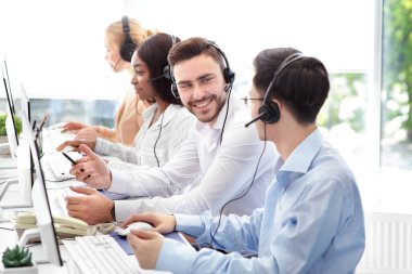 Mutlu erkek teknik destek operatörleri çağrı merkezinde dostça sohbet ediyorlar.
