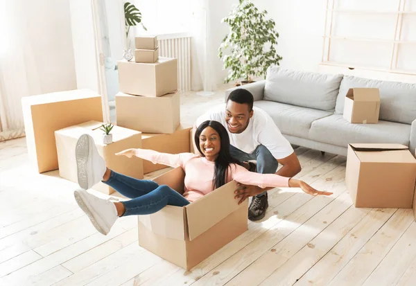 Mooie zwarte dame en haar jonge man spelen samen met kartonnen doos op bewegende dag — Stockfoto