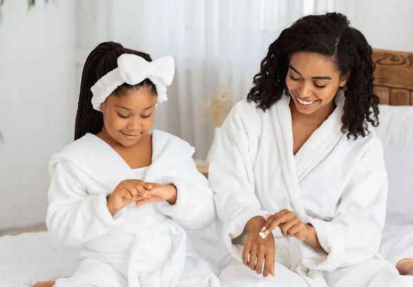 Klein Afrikaans meisje en haar moeder doet hand schoonheid behandeling thuis — Stockfoto