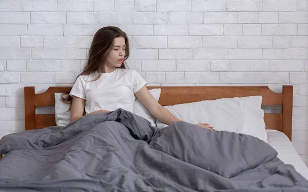 Несчастная молодая женщина, потерявшаяся в печальных воспоминаниях, вспоминающая своего покойного мужа, гладящая подушку на кровати дома, копирующая пространство — стоковое фото