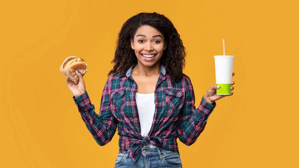 Funny afroamericana dama sosteniendo hamburguesa y bebida — Foto de Stock