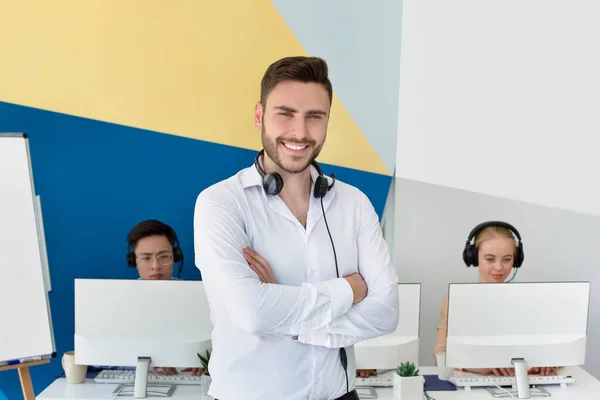 Porträt eines positiven männlichen Kundenbetreuers und seiner Kollegen im modernen Call Center — Stockfoto