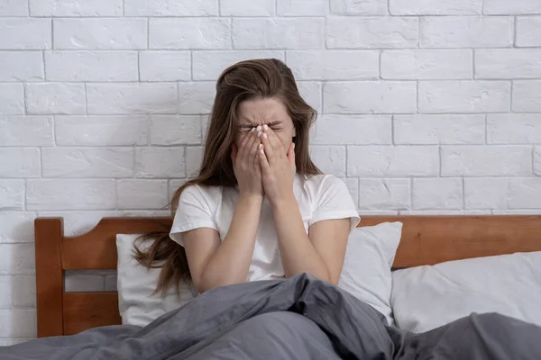 Depressed young woman covering her face and crying on bed at home — Stock Photo, Image