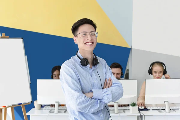 Asiatische männliche Techniker posieren mit verschränkten Armen im Callcenter — Stockfoto