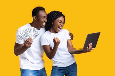 Duygusal siyahi çift laptop ve parayla kazanmayı kutluyor