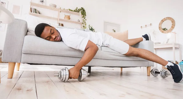 Afrikaanse man slapen op de bank na het uitputten van training thuis — Stockfoto