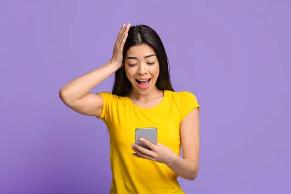 Mobiel aanbod. Verbazingwekkende aziatische vrouw met smartphone, kijken naar het scherm met opwinding — Stockfoto