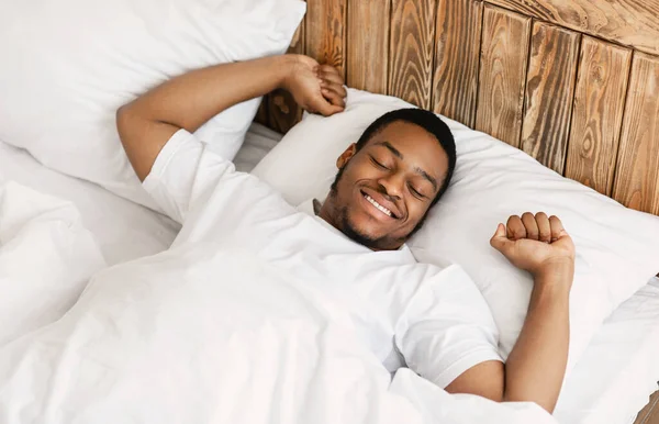 Alegre bem dormido homem africano acordar no quarto moderno — Fotografia de Stock