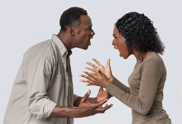Enojado negro hombre y mujer luchando sobre fondo gris —  Fotos de Stock