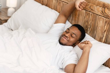 Dinlenmis siyah adam uyaniyor ve yatakta yatiyor.