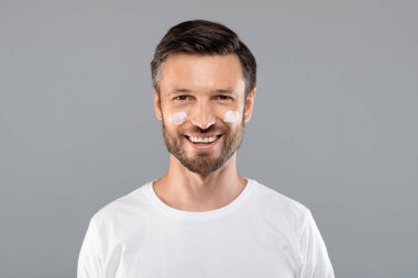 Yanakları kırışıklıklara karşı krem sürmüş orta yaşlı bir adam.