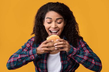 Orange Studio 'da hamburger yiyen komik siyahi kadının yakın çekimi.