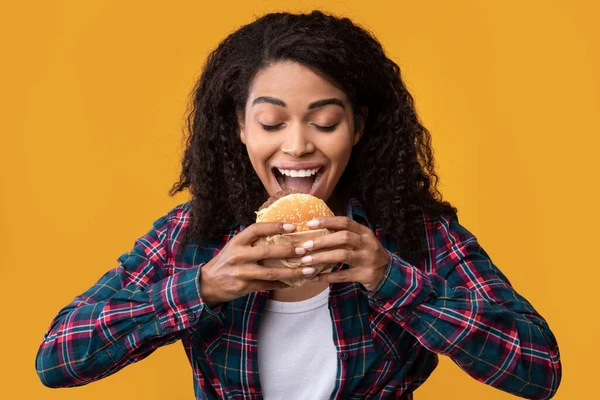 Primer plano de la divertida mujer negra comiendo hamburguesa en Orange Studio — Foto de Stock
