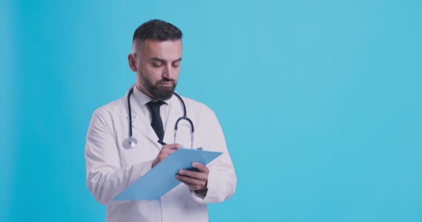 Un chequeo médico. Médico masculino escribiendo resultados de la prueba en bloc de notas, llenando la prescripción — Vídeos de Stock