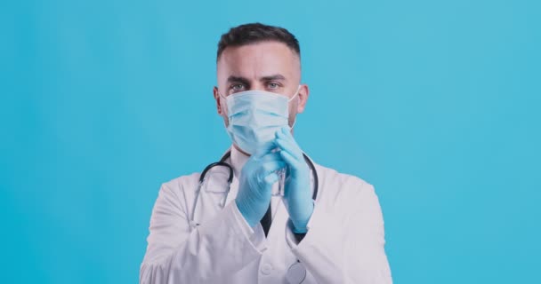 Coronavirus önleme. Tıbbi maskeli doktor ve eldivenli adam dezenfekte edici sprey dezenfektanı kullanıyor. — Stok video