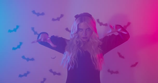 Halloween spell. Studio portrait of blonde lady gesturing, conjuring to camera in neon lights — Stock Video