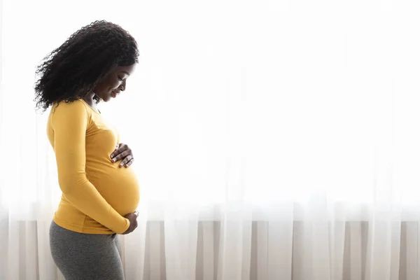Vacker gravid svart kvinna kramar magen hemma — Stockfoto