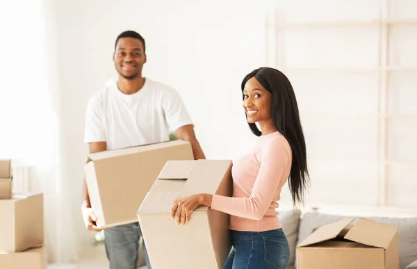 Μετακομίζω σε νέο σπίτι. Ευτυχισμένος μαύρος και η όμορφη κοπέλα του με κουτιά που ποζάρουν και χαμογελούν κατά τη μετεγκατάσταση — Φωτογραφία Αρχείου