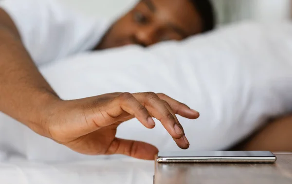Μαύρος άνδρας που κλείνει το ξυπνητήρι στο τηλέφωνο ξυπνώντας εσωτερικό — Φωτογραφία Αρχείου