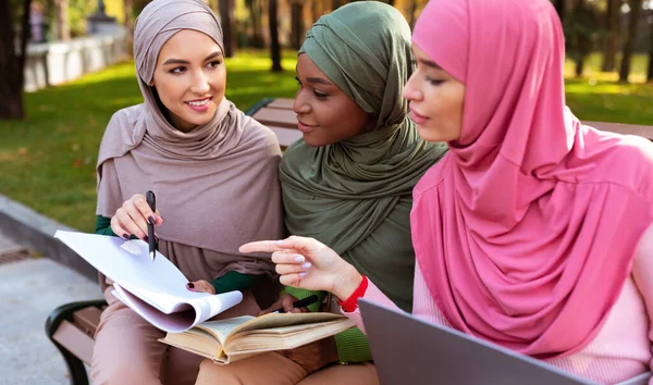 Tres señoras musulmanas aprendiendo a leer libros sentadas en el parque al aire libre — Foto de Stock