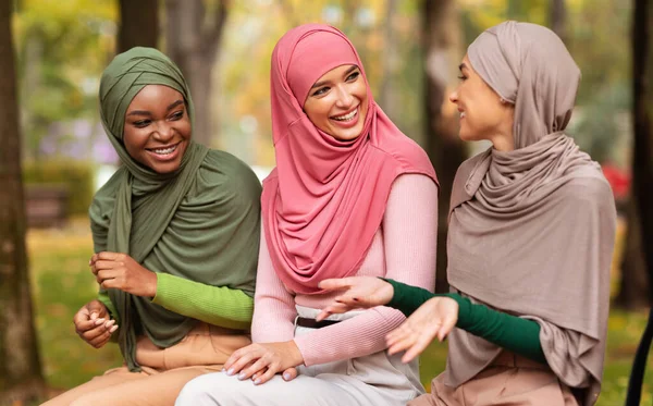 Tres señoras árabes hablando sentadas en el banco en el parque de la ciudad —  Fotos de Stock