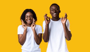 Kadın ve erkek umutla parmaklarını çaprazlayarak gözlerini kapatıyorlar.